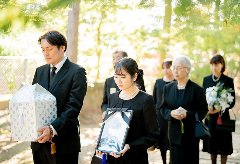 ご火葬とお骨上げを終え、ご遺骨と遺影を手にするご遺族